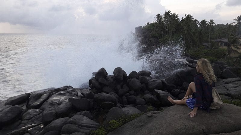 Atardecer en la playa de Unawatuna chica sentada olas y rocas