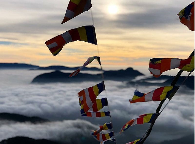amanecer, nubes y banderas en la subida a adams peak